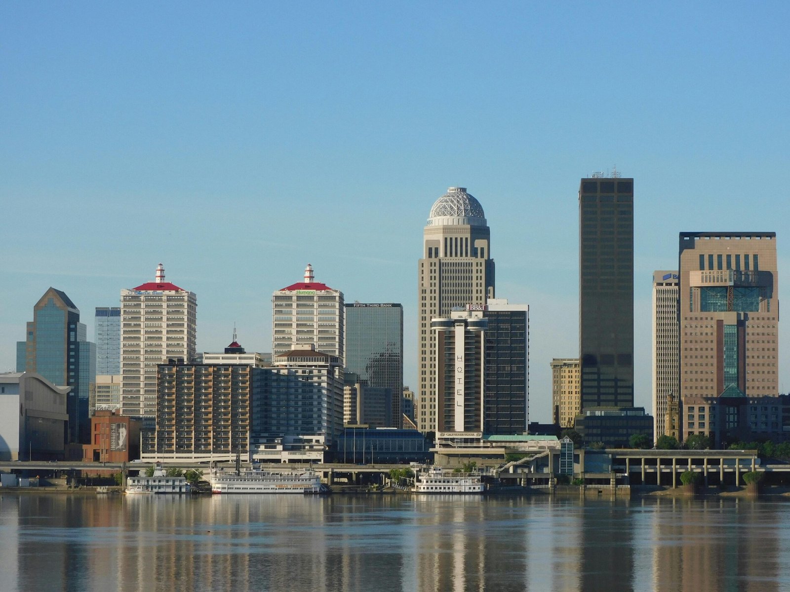 Stunning view of Louisville's skyline with modern skyscrapers reflecting on river.